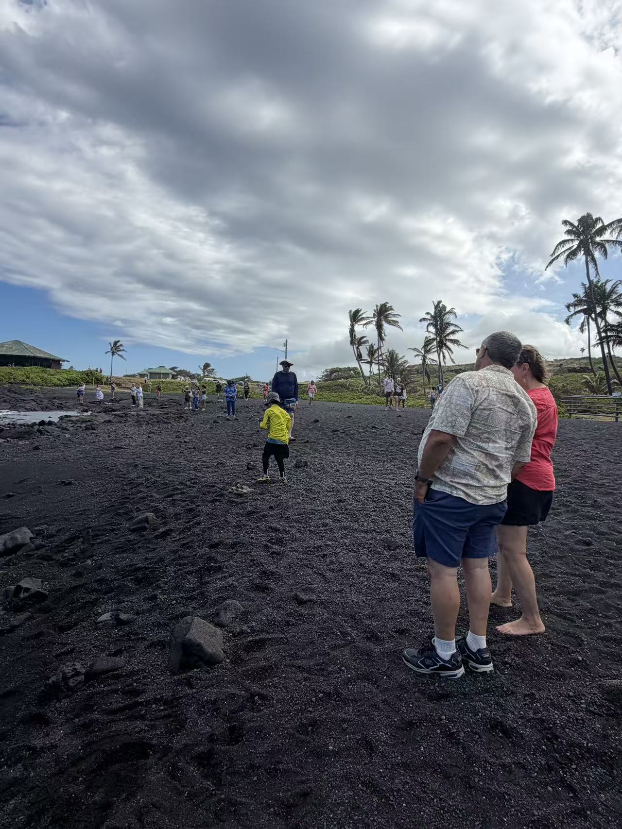 Guests walking across a black sand beach