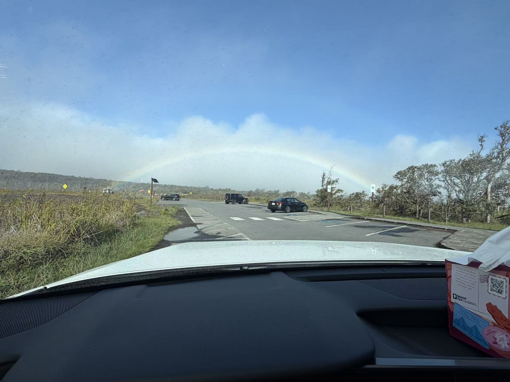 Driving through the volcanic landscape beneath a rainbow